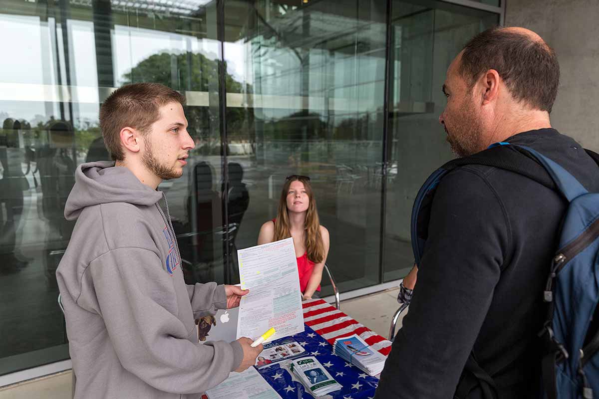 Aaron Vad, president of CI College Democrats, registers students to vote during a campus registration drive.