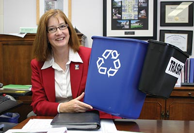 Deborah Wylie holds up a much larger recycle bin alongside a smaller trash can