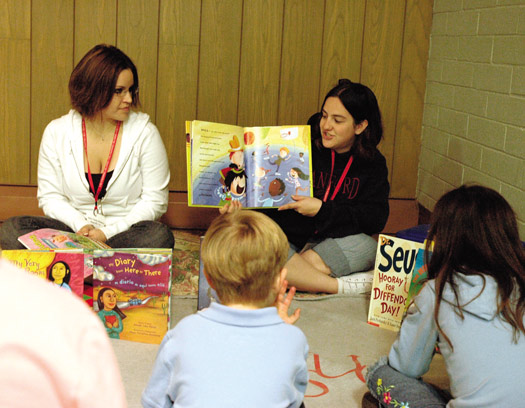 Two adults reading to children