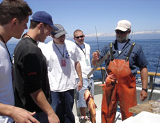 The students and the fisherman examine the freshly-caught fish.