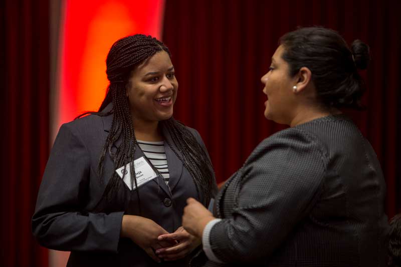 Two women in suits facing each other speaking at a presentation