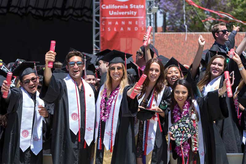 Group of CSUCI graduation students in black cap and gowns smiling