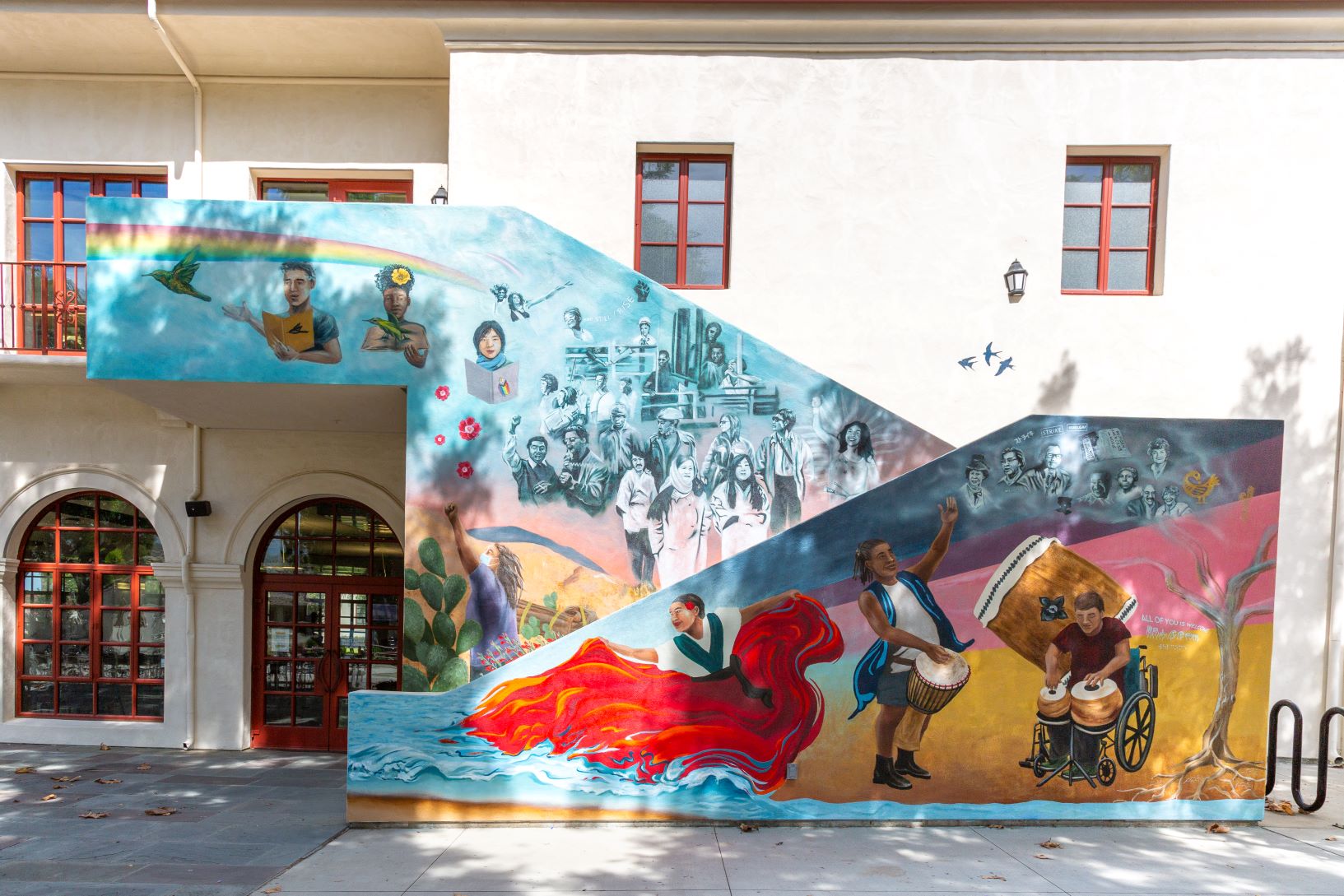 peson with open book gesturing to flying bird,rainbow above them,person holding open book with bird on book,group of historical figures,flamenco dancer bright red skirt flowing into water,person standing holding drum and person in wheelchair with drum