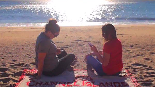 Two people on a towel on the beach with the sun reflecting on the ocean in the background