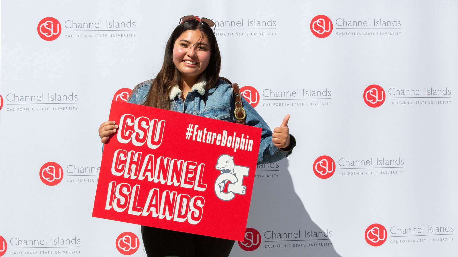 Female future CSUCI student holding a poster board that reads CSU Channel Islands #FutureDolphin