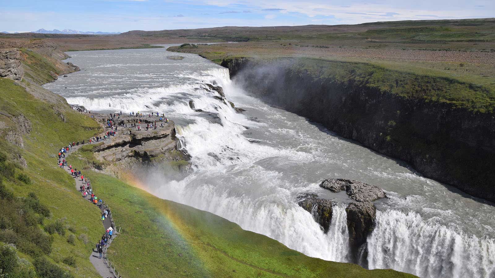 Large waterfall in Iceland with toursits walking towards the waterfall