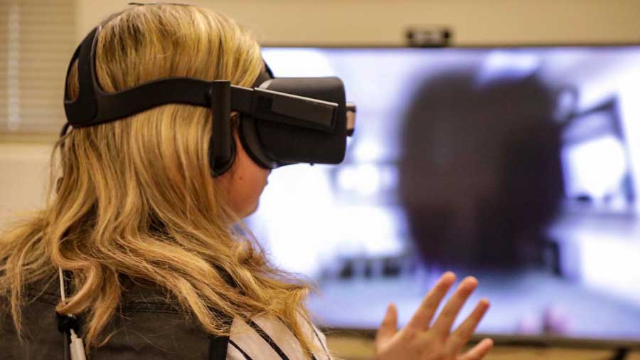 Female student wearing a Virtual Reality headset while testing the embodied labs training