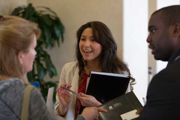 Three associates speaking with their focus on the woman on the left, while the other two are smiling