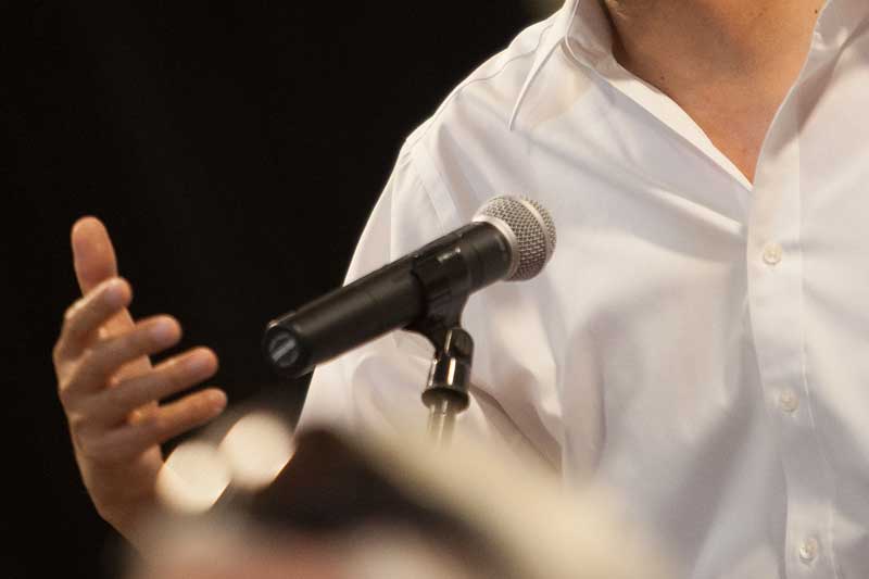 Close up of a person in a white button up in front of a microphone