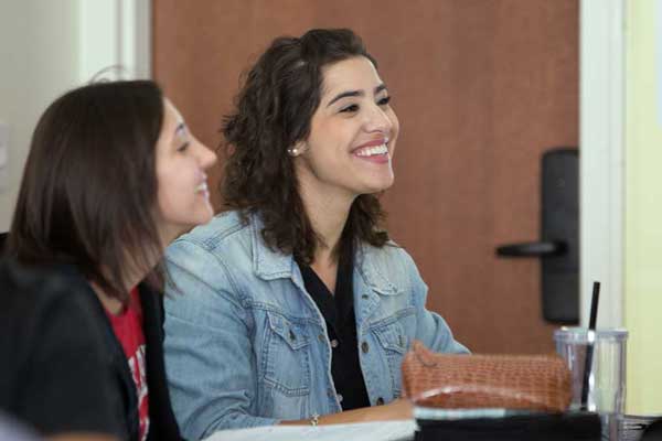 Two smiling students sitting down in a classroom
