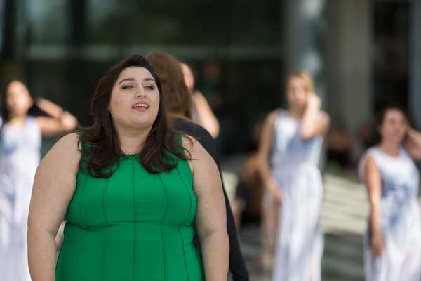 A brunette woman singing wearing a green dress 