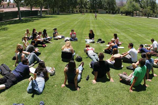 Group of students sitting on a grass field in a circle