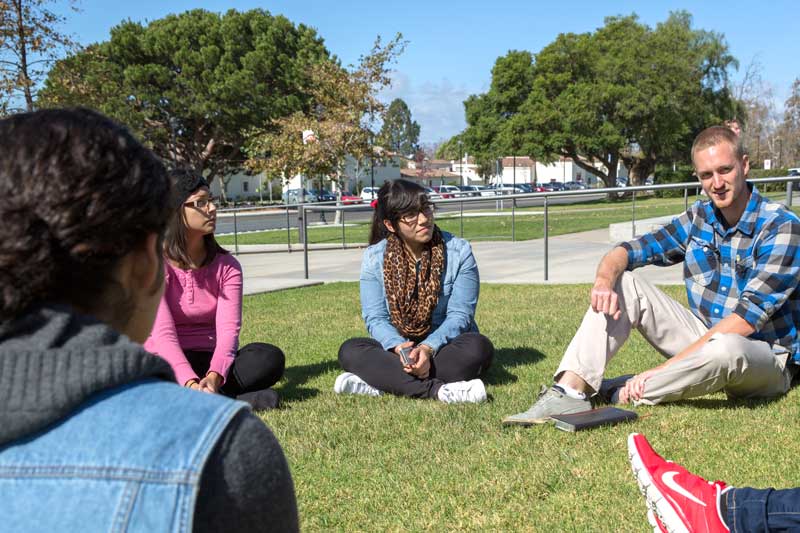 Close up of a group of students sitting on a grass field in a circle