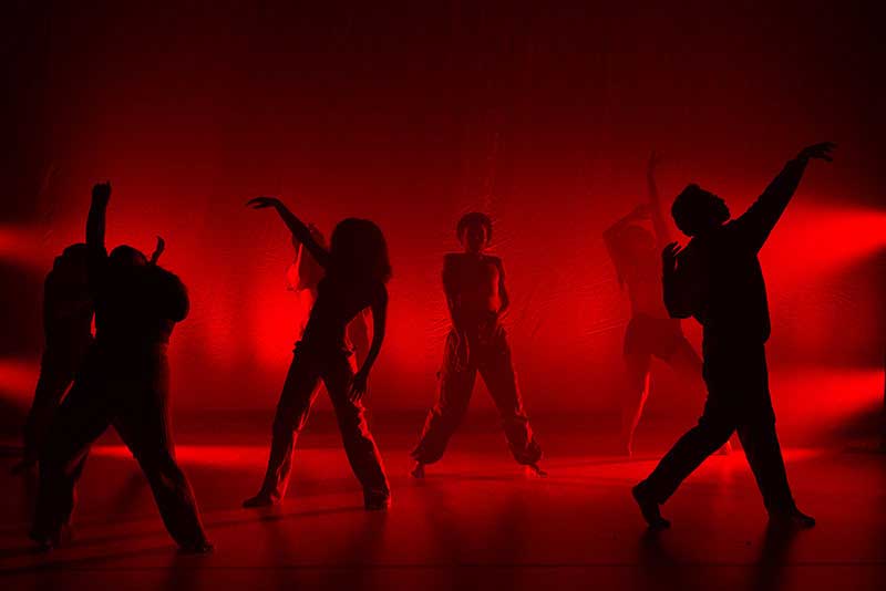 Group of students dancing on a floor under red lights