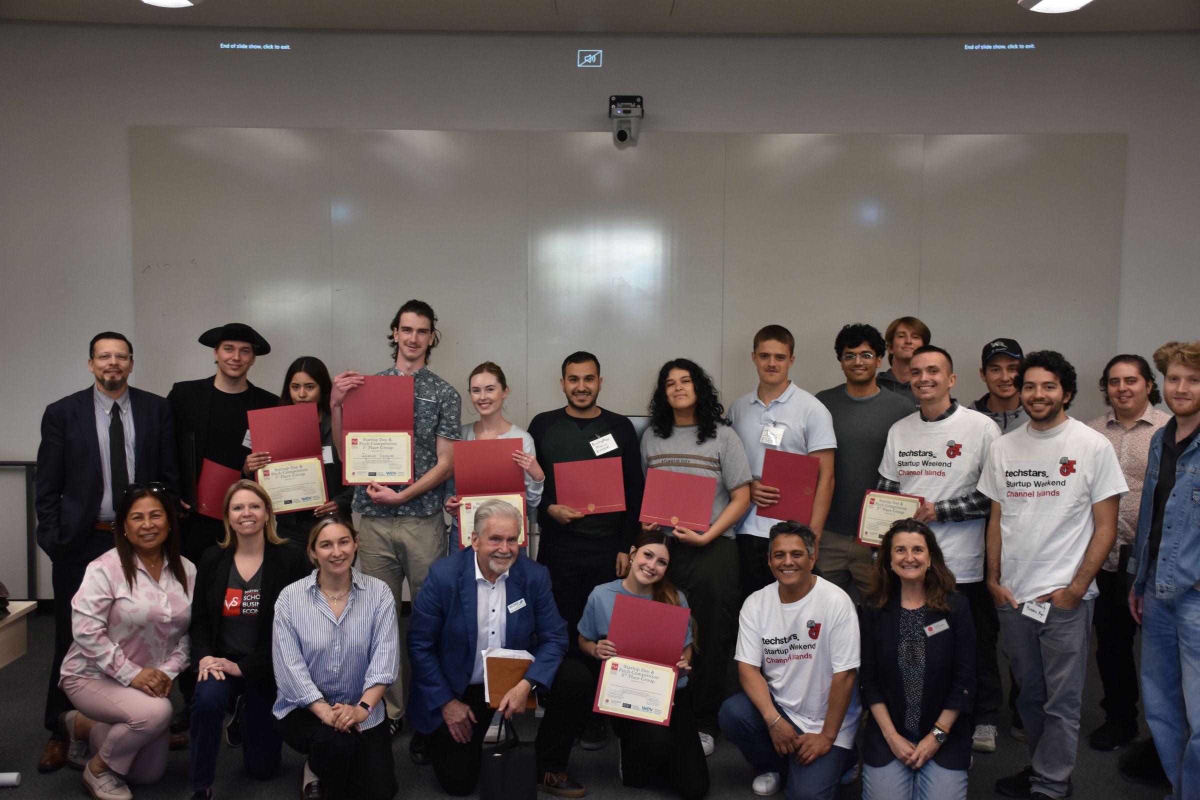 Students taking a group pic with their awards