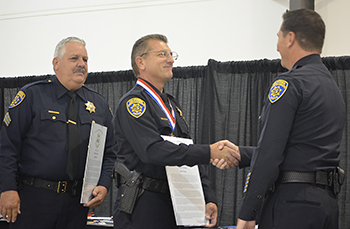 Chief John Reid congratulates Officer Stephen Osman and Sergeant Jeff Cowgill.