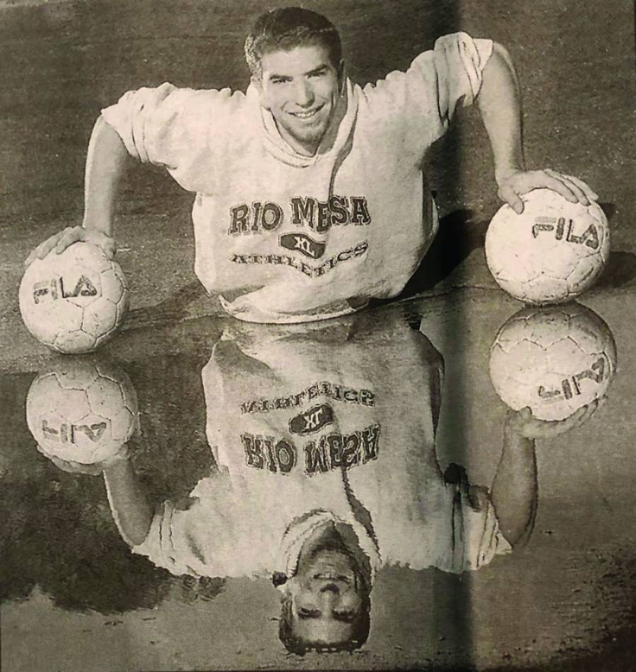 Trying not to fall in the puddle, Jonathan Johnen carefully balances on two soccer balls for this senior year photo at Rio Mesa High School.