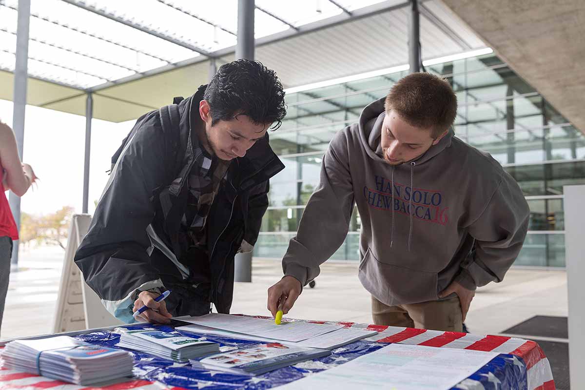 Aaron Vad, president of CI College Democrats, registers students to vote during a campus registration drive.