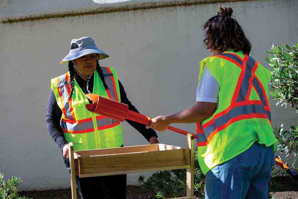 Yeneth Renteria holds the screen while Karisa Smathers unloads a soil sample from the auger.