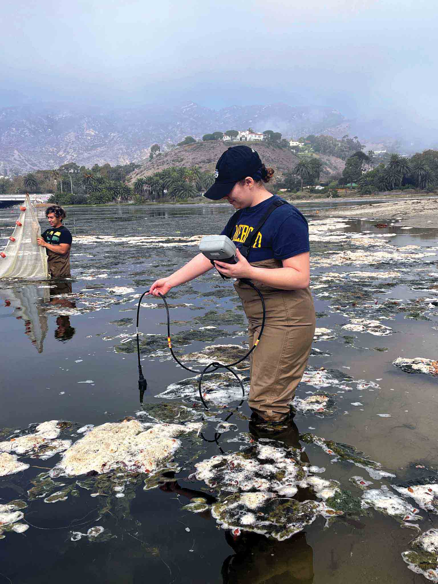 Adalhia Estrada takes water quality measurements while Bryan Loya Acevedo pulls a net through the Malibu Lagoon.