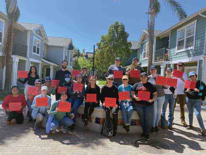 Center for Community Engagement Community Partnership Lead Jennifer Raymond, fifth from right, takes an advocacy photo with other Farmworker Immersion Project participants at Villa Cesar Chavez Apartments. 