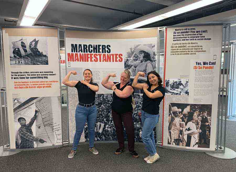 Hannah Lovett, Rebecca Hyde Gonzales and Catherine Cervantes pose in front of the exhibit that they helped install.