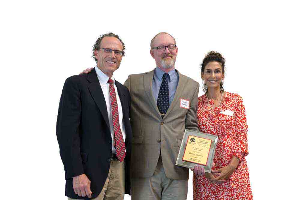 Dennis Downey, center, poses with Professor of History Jim Meriwether and Pilar Pacheco after receiving an award for his service as Faculty Director of the Center for Community Engagement in 2018.