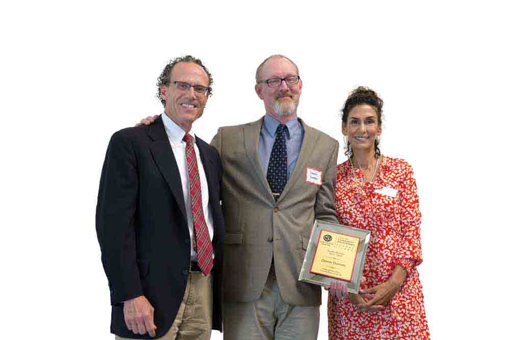 Dennis Downey, center, poses with Professor of History Jim Meriwether and Pilar Pacheco after receiving an award for his service as Faculty Director of the Center for Community Engagement in 2018. Dennis Downey, center, poses with Professor of History Jim Meriwether and Pilar Pacheco after receiving an award for his service as Faculty Director of the Center for Community Engagement in 2018.