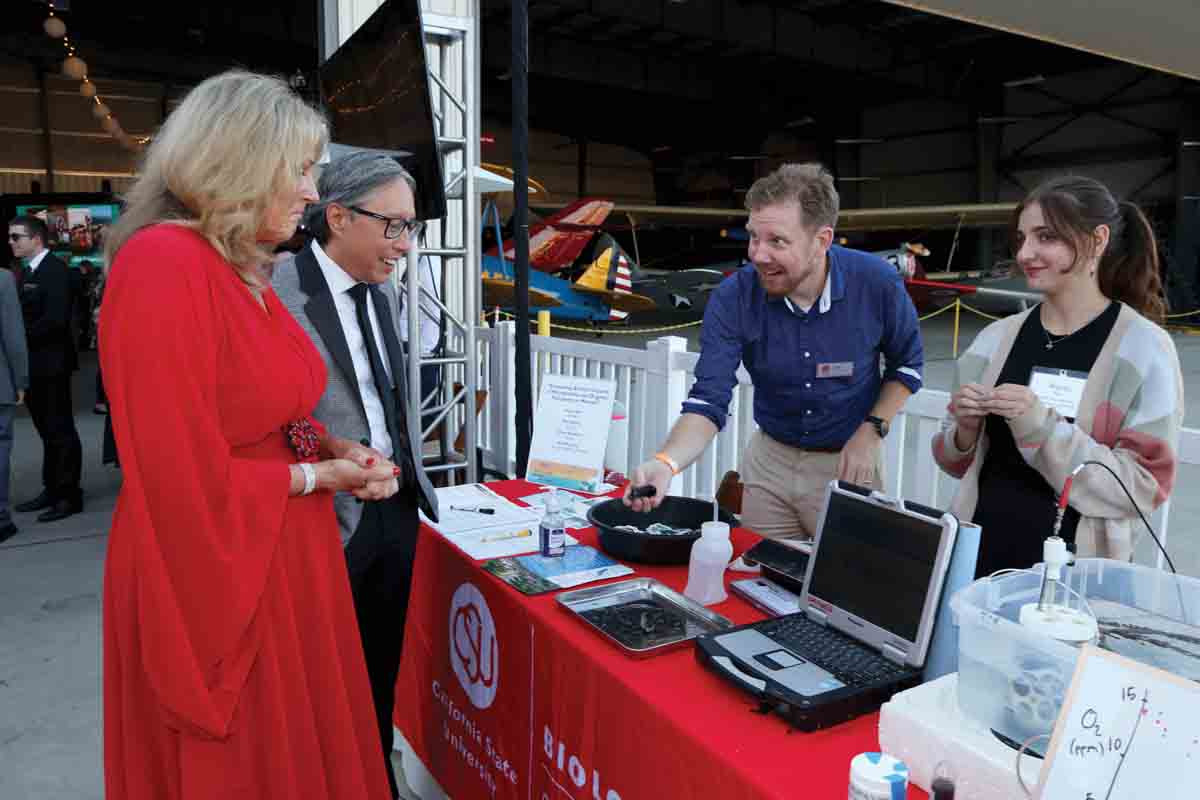 Professor Geoffrey Dilly explains a microplastics community research project to President Yao and his wife CJ. Student researcher Alyssa Mak also assisted with the research project.