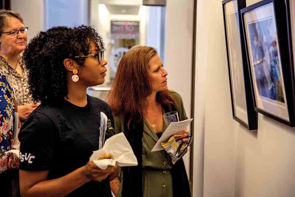 LEFT Staff and faculty examine photos during an opening reception.