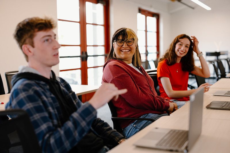 Three students sitting at a table talking
