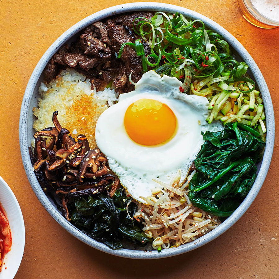 Photo shows a bowl of bibimbap containing meat and vegetables topped by an egg.