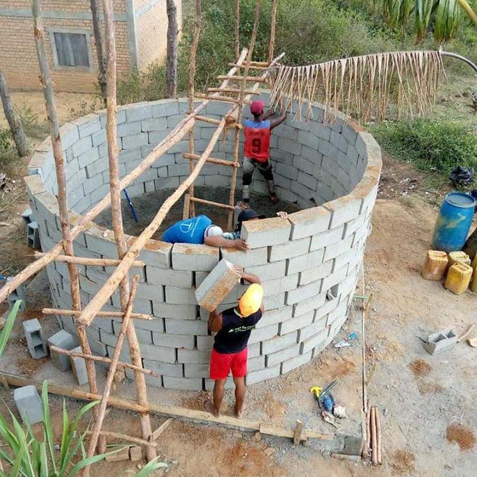 Residents of a village in Madagascar work on building a well