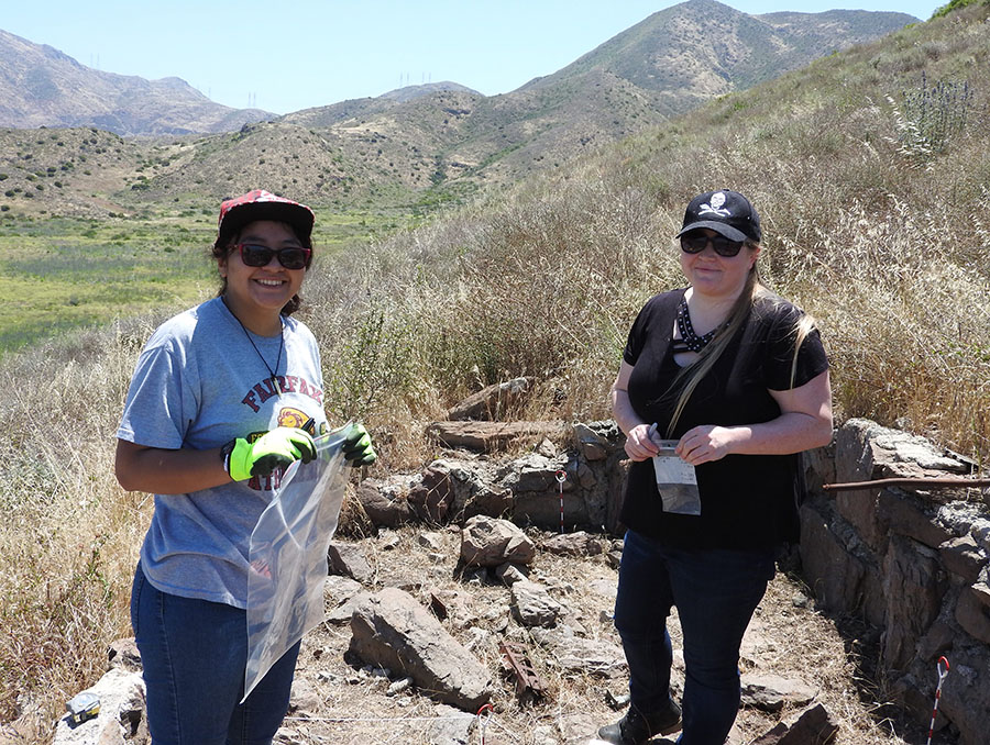 students stand outside at an excavation site as they carefully comb through the area