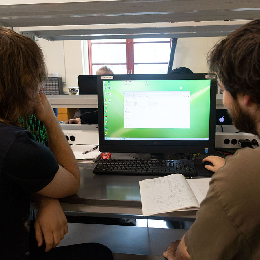 A tutor helps a student with an assignment on a computer.