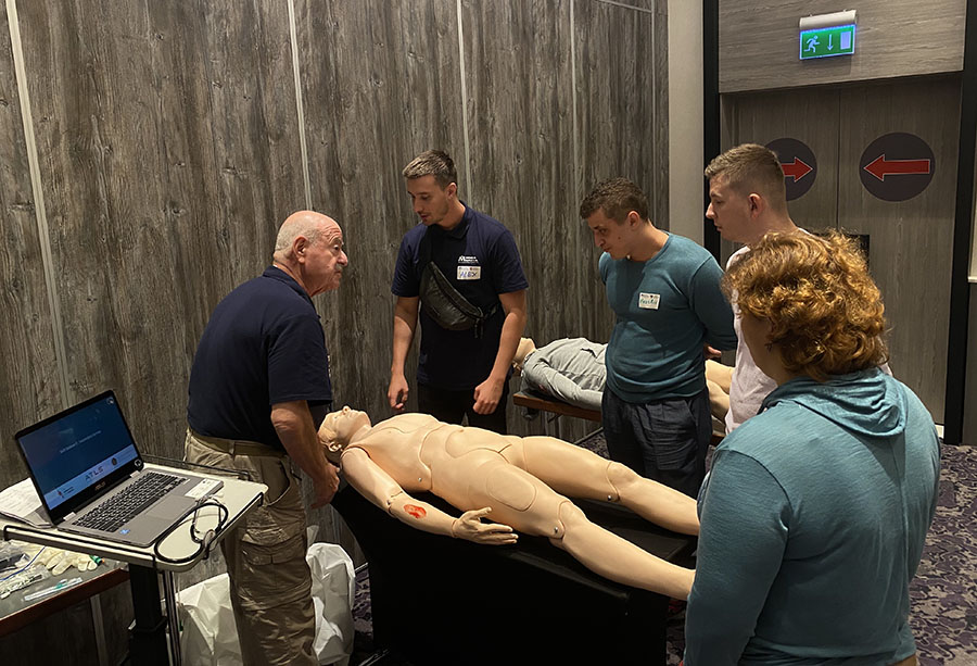 Dr. Baker stands with three citizens as he teaches them a Stop the Bleed technique on a mannequin