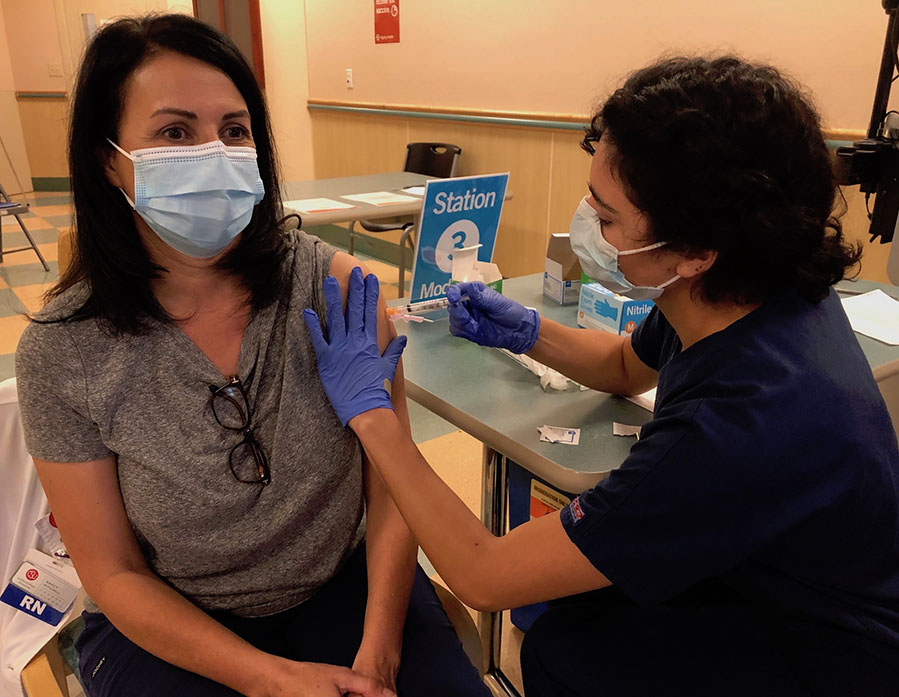 Nursing student administering COVID-19 vaccine to faculty member