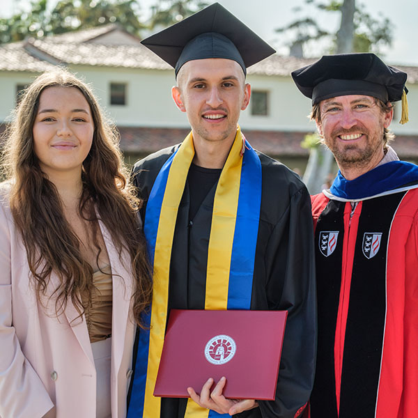 Oleksandr Nikolenko (center), stands center, flanked by his wife and Comp Sci professor Brian Thoms