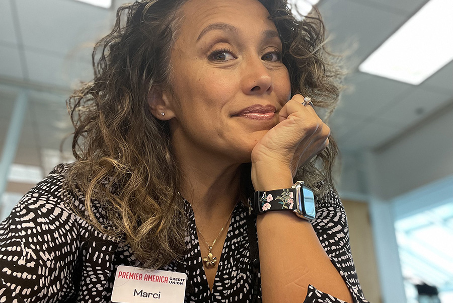 Marci Francisco, wearing a Premier America Credit Union name badge, with her chin resting in her hand.