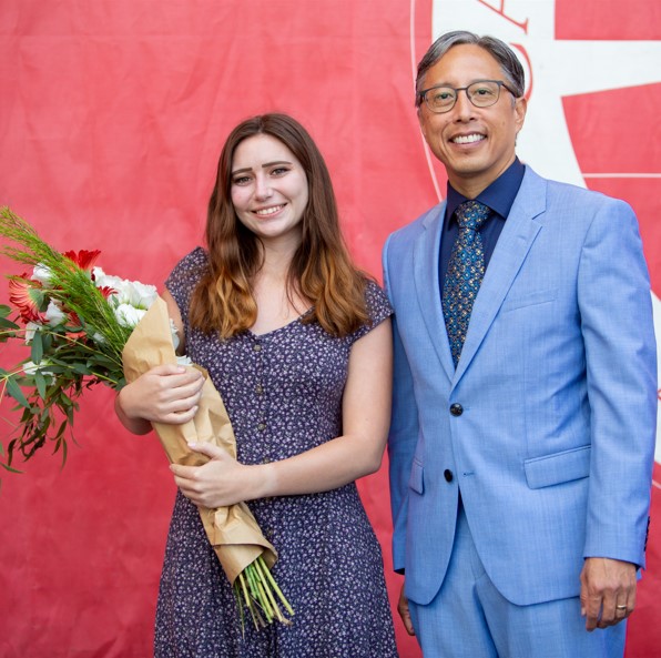 Sheradyn Ruef, student awardee, receiving flowers and smiling with President Yao