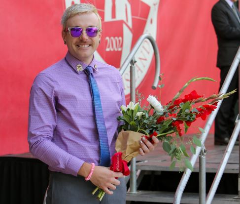 trent ruiz standing smiling with a bouquet of red and white flowers