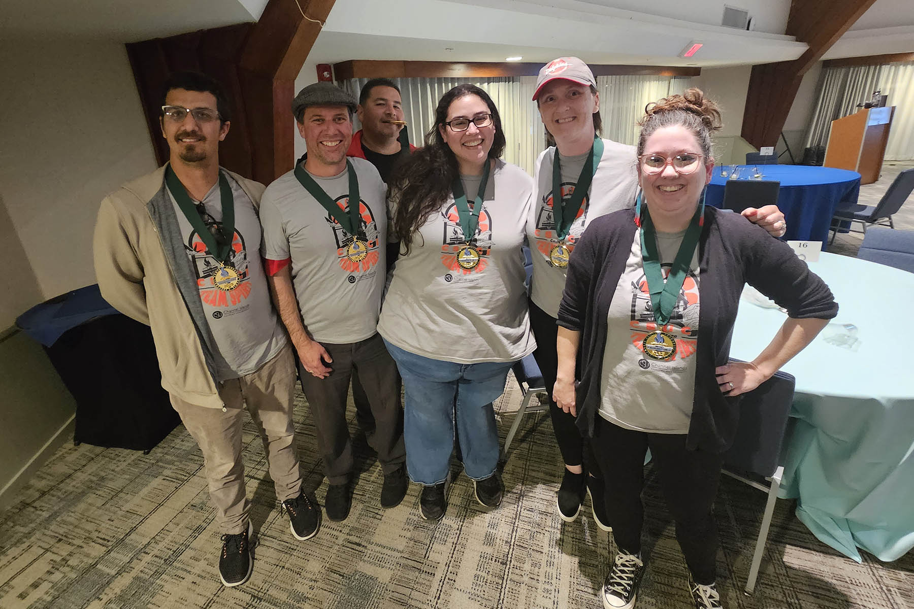Six people wearing gold medals posing for the camera