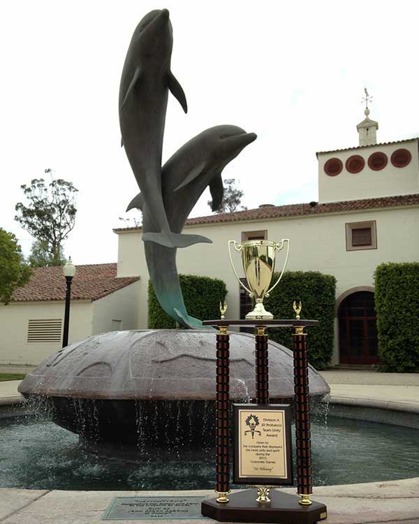 A photo of a trophy in front of a dolphin fountain.