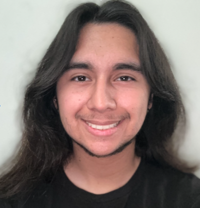 alexander velasquez is wearing a black shirt and smiling at the camera. He has long black hair and is latino