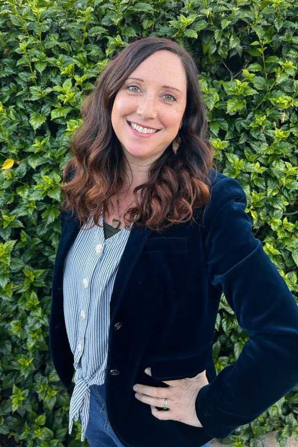 Leslie in a professional outfit in front of some leaves