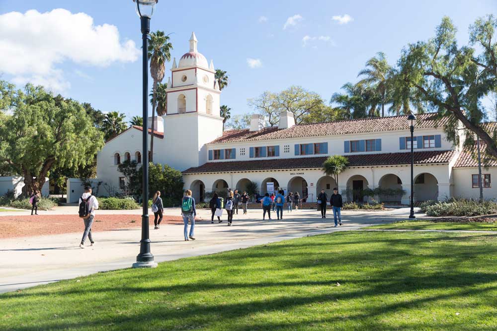 Spanish style architecture Bell Tower building with students walking in front of it on a sunny day 